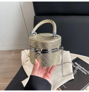 Makroaufnahme der goldenen Zylinder-Abendtasche mit Steppmuster und Metallgriff-Details