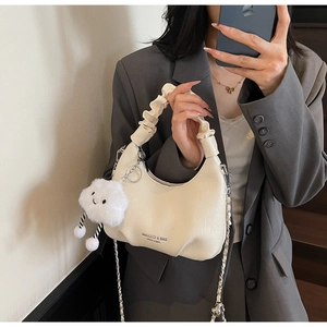 Détail du sac hobo crème avec plis nuages, chaîne argentée et breloque peluche