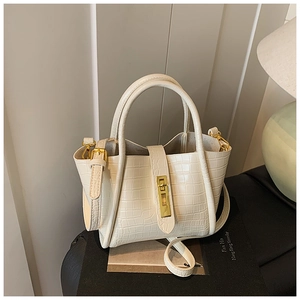 Detail of cream crocodile embossed handbag featuring gold twist lock and dual handles