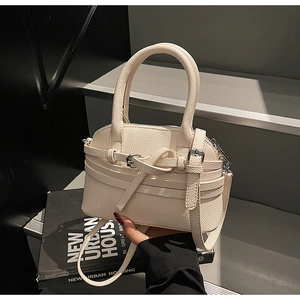 Détail du sac à main en cuir grainé blanc cassé avec boucles argentées et sangles croisées