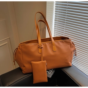 Vue détaillée du grand sac cabas tressé avec pochette assortie sur une chaise