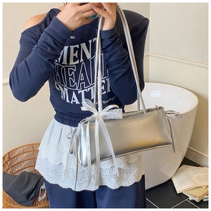Detail of silver rectangular shoulder bag with white lace bow and dual straps
