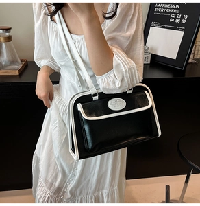 Détail du sac à main contrasté noir et blanc porté avec une robe blanche plissée