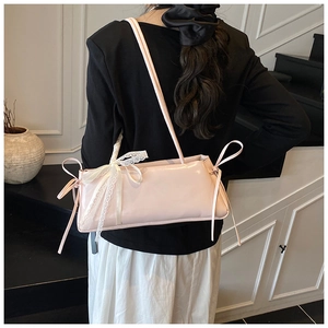Detail of light pink patent leather shoulder bag with white lace bow decoration