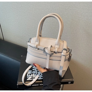Détail du sac à main en cuir grainé blanc cassé avec double poignée et boucle dorée