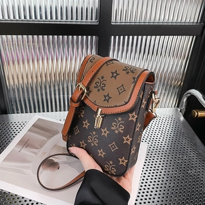 Detail of vintage patterned crossbody bag with gold twist lock and brown leather texture