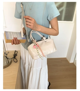 Detailed side view of cream white leather bucket bag with pink heart charm and woven strap