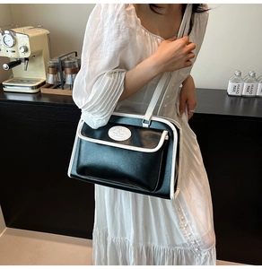 Détail du sac bandoulière vintage contrasté noir et blanc porté par un mannequin en robe