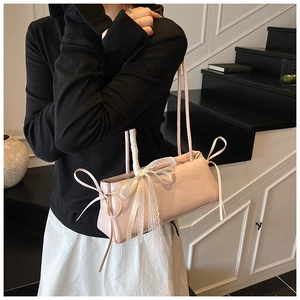 Close-up of pink rectangular shoulder bag featuring white lace and silk bow detailing
