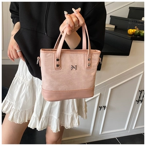 Detail of pink canvas bucket bag with leather trim and gold logo lettering