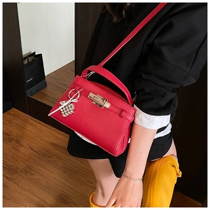 Detail view of red lychee grain leather handbag with decorative heart bead charm
