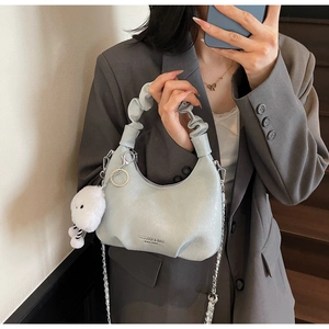 Détail du sac dumpling plissé bleu clair avec chaîne argentée et charm en peluche blanc