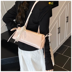 Detail of pink patent leather shoulder bag with chic bow and lace edge trim