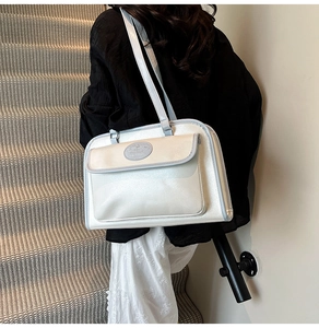 Détail du sac à bandoulière crème en similicuir brillant avec logo embossé et fines coutures