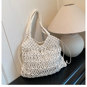 Detail of hollow-out cotton crochet beach bag with drawstring liner on black shelf