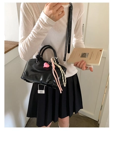 Detailed shot of black minimalist handbag with heart charm and shoulder strap