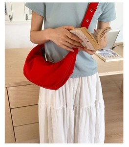 Red nylon crescent crossbody bag with pleated texture and silver eyelet strap