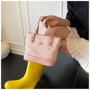 Detail view of pink textured fabric bucket bag with leather trim and silver logo