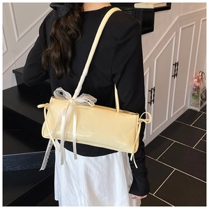 Detail view of cream yellow shoulder bag with lace bow and elegant leather texture