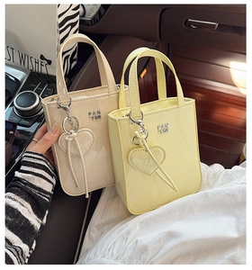 Detail of cream and yellow patent leather handbags with heart charms on car seat