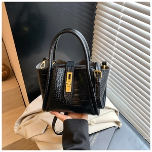 Detail of black crocodile texture bucket bag with elegant gold metal hardware buckle