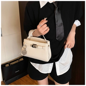 Detail of off-white lychee grain leather handbag with silver lock and heart charm