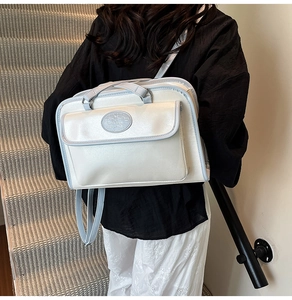 Vue détaillée d'un sac à bandoulière blanc avec bordure bleue porté par un mannequin