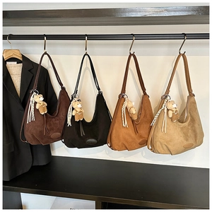 Detail view of four suede crescent bags in earth tones with plush bear charms and tassels