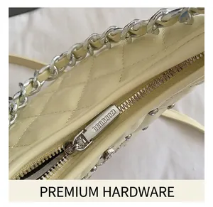 Macro detail of silver metal zipper with engraved logo and quilted pattern on beige bag