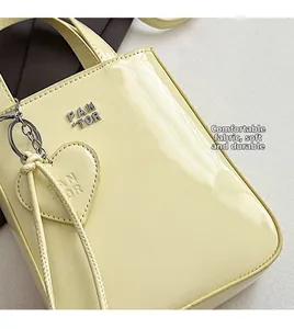 Detail of yellow patent leather handbag with heart charm and Pan Tor metal logo