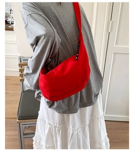 Detail of red crescent shoulder bag worn by model in a minimalist interior setting