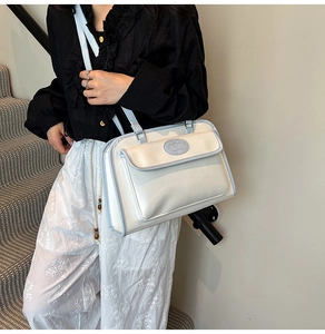 Détail d'un sac à bandoulière vintage beige et bleu avec un logo ovale sur le rabat avant