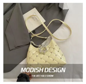 Detail of quilted cream shoulder bag with rhinestone studs and silver chain strap