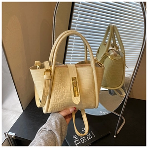 Detail view of cream faux crocodile texture and gold metal lock on bucket bag