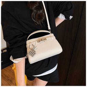 Close-up of cream pebble leather Kelly bag with metal lock and heart charm