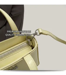 Detailed close-up of glossy cream yellow patent leather bag with silver metal hardware
