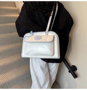 Détail du sac blanc iridescent en cuir perlé avec bordure bleu clair porté par un mannequin
