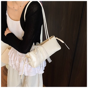 Detail of minimalist beige underarm bag with elegant white lace bow and long ribbons
