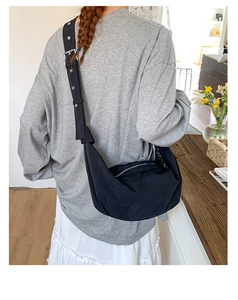 Detail of black nylon crescent bag with adjustable grommet strap and silver metal zipper