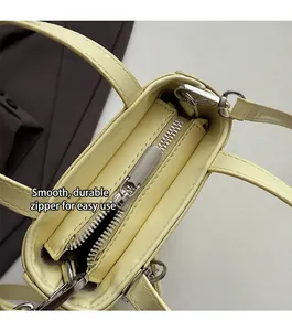 Detail view of the smooth metal zipper closure on this elegant beige crossbody bag