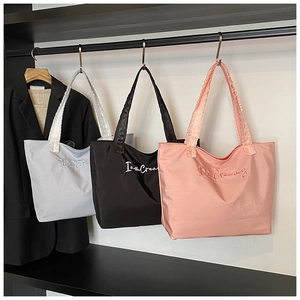 Detail of glossy fabric tote bag with I am Creamy embroidery and pleated shoulder strap