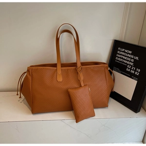 Détail de la texture tressée du sac fourre-tout camel et de sa pochette assortie