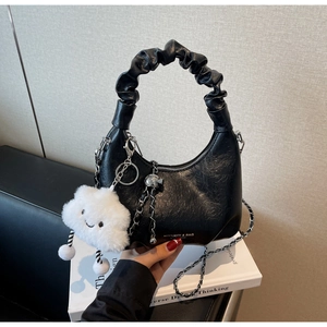 Détail du sac noir avec poignée plissée, chaîne argentée et pendentif nuage en peluche
