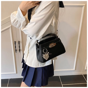 Detail of black lychee grain leather Kelly bag with gold lock and pearl grape charm