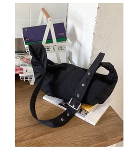 Detail of adjustable wide shoulder strap with metal eyelets on a black hobo bag