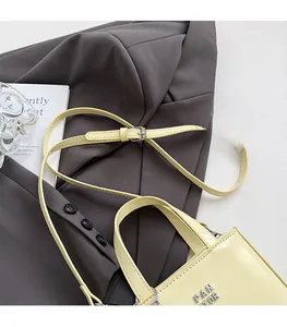 Detail of adjustable shoulder strap and metal buckle on a beige glossy handbag