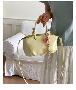 Close-up of cream leather bucket bag with knot handle and heart charm detail