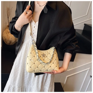 Close-up of quilted handbag with silver star logo and stud details on cream leather