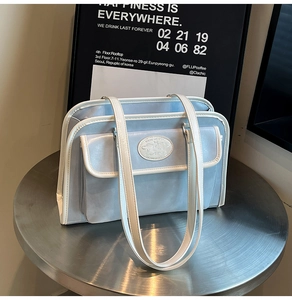 Détail d'un sac à main bleu clair avec bordure blanche sur une table de café
