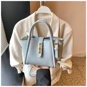 Close-up of light blue crocodile embossed leather bucket bag with golden twist lock detail